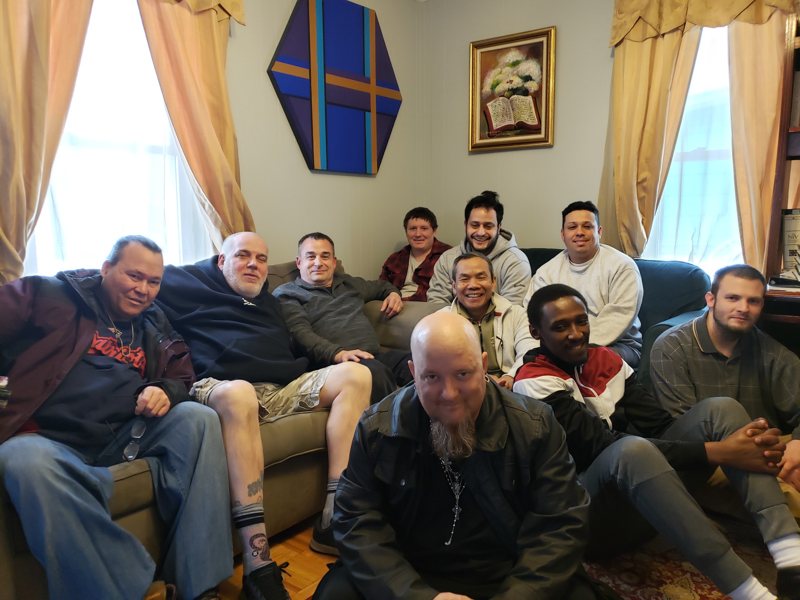 Ten men gathered in a living room.