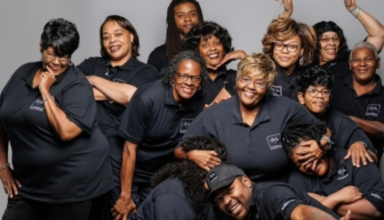 Group of smiling staff wearing black shirts.